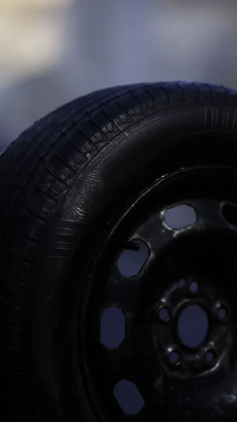 Close view of a black car tire with distinct tread patterns and rim shine Stock Footage 341402486