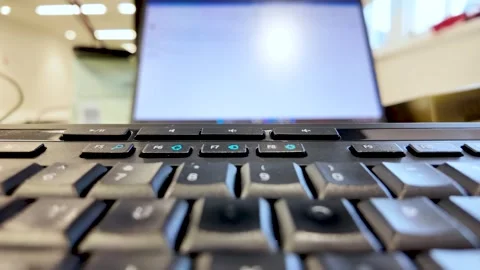 Close up view of a black computer keyboard with a laptop screen visible in the Stock Footage 327830355
