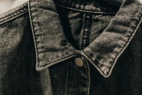 Close-up view of a black denim jacket collar with stitching details and a b.. Stock Photos