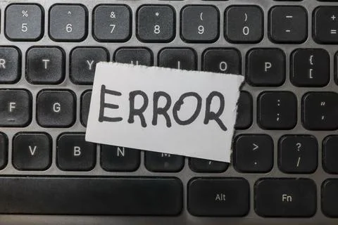 A close-up view of a black keyboard with a paper note labeled ERROR placed on Stock Photos