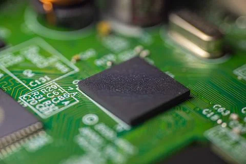 Close-up view of a black microchip on a green printed circuit board with in.. Stock Photos