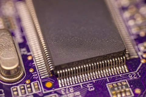 Close-up view of a black microchip mounted on a purple printed circuit boar.. Stock Photos