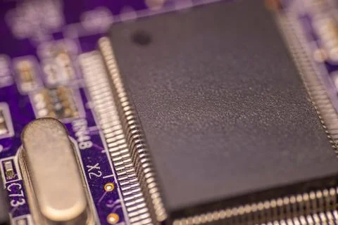 Close-up view of a black microchip mounted on a purple printed circuit boar.. Stock Photos