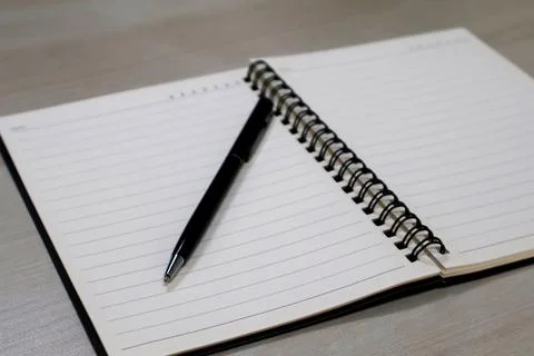 Close up view black pen on a notebook with lines page Stock Photos