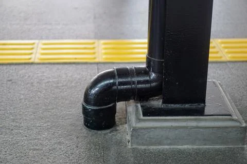 A close-up view of a black plastic wastewater piping installation beneath Stock Photos