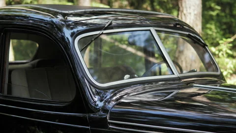 A close-up view of a black retro car in a summer green forest Stock Footage 201626767