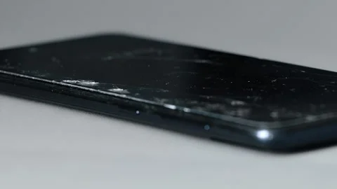 Close up view of black smartphone with fractured glass screen protector lying on Stock Footage 344863703