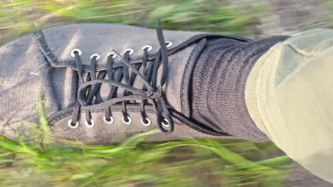 Close-up view of a black sneaker stepping on grass and dirt Stock Footage 336686963