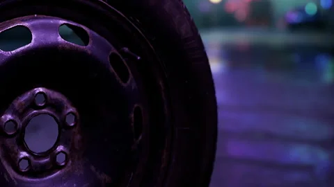 Close up view of a black tire on a wet road showing reflections at night Stock Footage 342802480