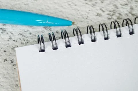 Close view of a blank spiral notebook with a turquoise pen on a textured ba.. Stock Photos