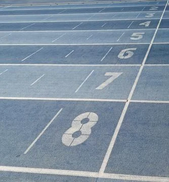 Close view of blue athletic running track with white lane numbers seven and.. Foto stock