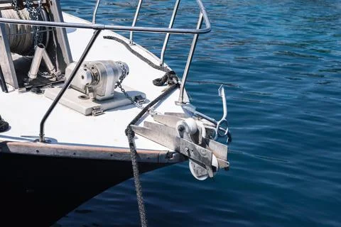 Close-up view of a boat bow featuring anchor equipment and calm blue sea wate Stock Photos