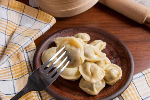 Close up view of boiled meat dumpling on metal fork. Served in clay plate U.. Stock Photos