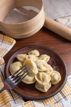 Close up view of boiled meat dumpling on metal fork. Served in clay plate Ukr Stock Photos