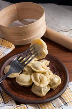 Close up view of boiled meat dumpling on metal fork. Served in clay plate Ukr Stock Photos