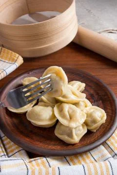Close up view of boiled meat dumpling on metal fork. Served in clay plate Ukr Stock Photos
