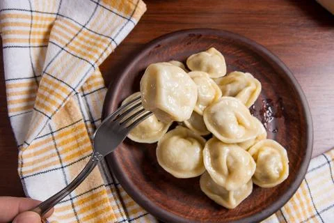 Close up view of boiled meat dumpling on metal fork. Served in clay plate Ukr Stock Photos