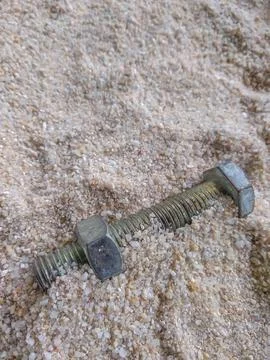 Close-up view of bolt and nut on the sand Stock Photos