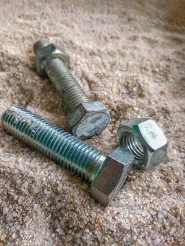 Close-up view of bolts and nuts on the sand Stock Photos