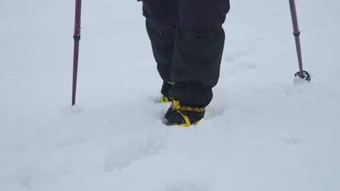 Close up view of boots with crampons and poles as person walks through Video stock 249048094
