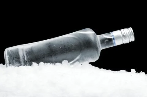 Close-up view of bottle of vodka lying on ice on black Stock Photos