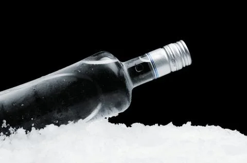 Close-up view of bottle of vodka lying on ice on black Stock Photos