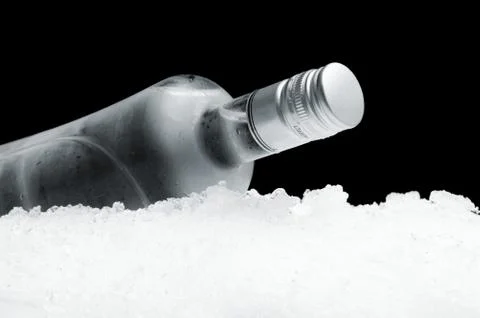 Close-up view of bottle of vodka lying on ice on black Stock Photos