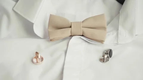 A close view of a bow tie and cufflinks arranged neatly on a white dress shirt Stock Footage 345642962