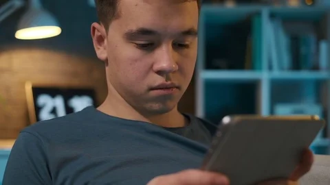 Close-up view of a boy attentively looking at his tablet while sitting on a Stock Footage 107547758