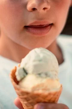Close-up view of a boy eating ice cream in a waffle cup. Macro. Detailed view of Stock Photos