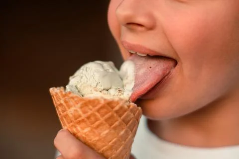 Close-up view of a boy eating ice cream in a waffle cup. Macro. Detailed view of Stock Photos