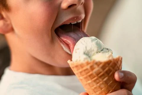 Close-up view of a boy eating ice cream in a waffle cup. Macro. Detailed view of Stock Photos