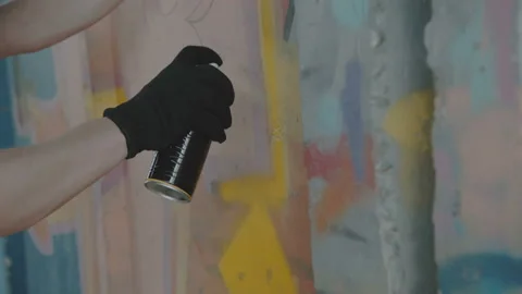 Close-up view of boy secretly drawing colorful graffiti on street wall 库存影片 95020126