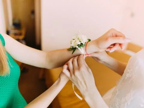The close-up view of the bride`s hands tying the wedding wristband on the hand Stock Photos