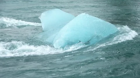 Close up view of a bright blue iceberg floating in the strong current of a Stock Footage 346327204