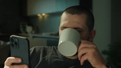 Close up view of a brunette man drinking coffee and using smartphone while Stock Footage 269139122