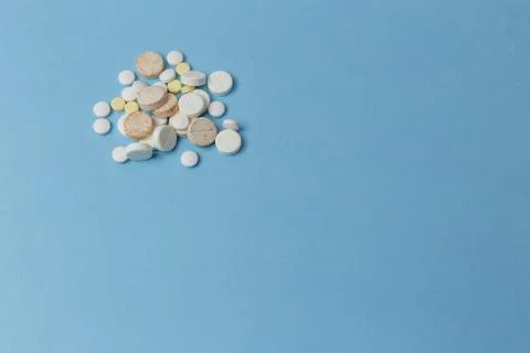 A close up view of a bunch of pills various kinds lay down a light blue surface Stock Photos