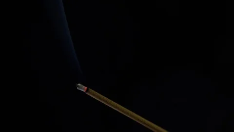 Close-up view of burning incense stick. Smoke blows from end of hot ember. Scent Stock Footage 129791801