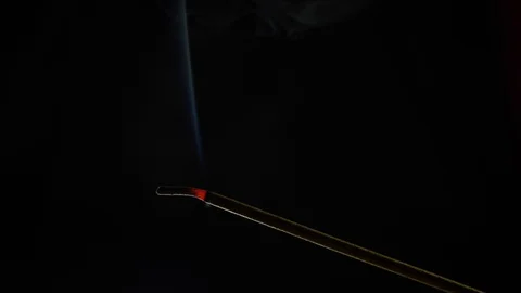 Close-up view of burning incense stick. Smoke blows from end of hot ember. Scent Stock Footage 129791871