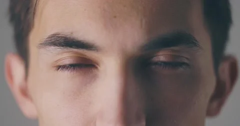 Close-up view of a calm young man is opening his eyes and looking to the camera Stock Footage 146342220