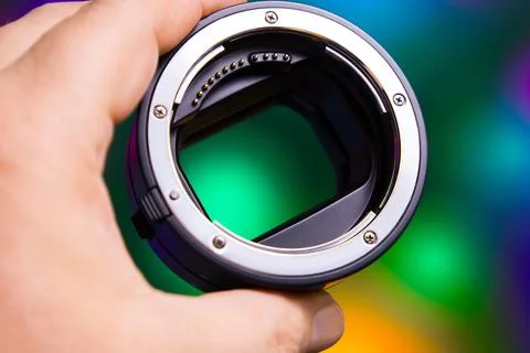 Close view of a camera lens mount held in a hand against a colorful background 写真素材
