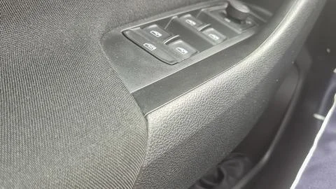 Close-up view of a car door control panel showing window buttons and a textured Stockfoto's