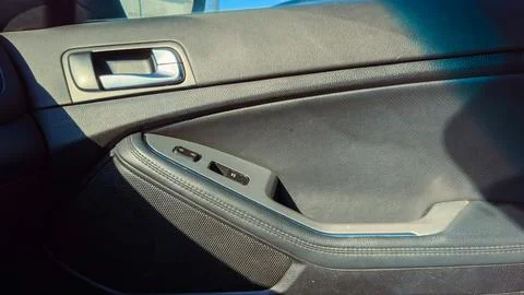 Close view of a car door panel with window controls, taken during daylight .. Stock Photos