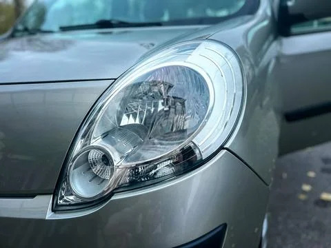 Close up view of a car headlight with open door and shiny surface in an urb.. Stock Photos