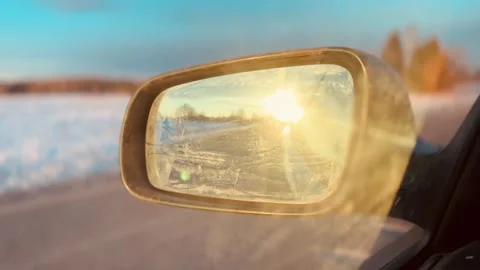 Close-up view of a car rearview mirror reflecting bright sun at sunset. Stock Footage 328228657