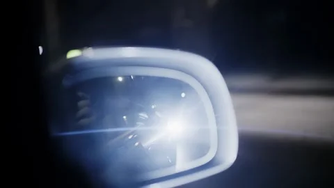A close up view of a car side mirror showing bright headlights of a vehicle.. Stock Footage 339765861