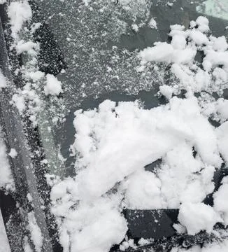A close-up view of a car windshield covered with thick, fresh snow, illustrating Stock Photos