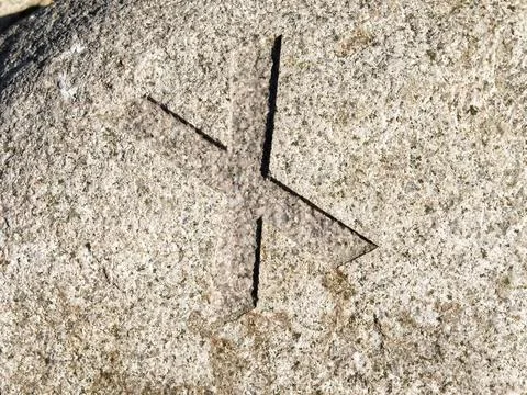 A close-up view of a carved stone featuring a cross-like symbol etched into.. Stock Photos