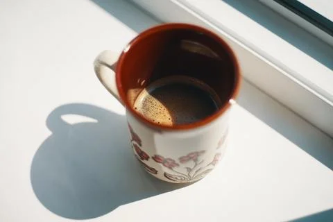Close-up view of a ceramic mug filled with fresh hot coffee on a white wind.. Stock Photos