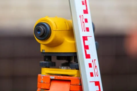 Close-up view of cheap geodesy level device with tower ruler outdoors Fotos Stock